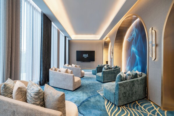Un moderno vestíbulo de hotel con una pantalla plana grande, zonas de estar cómodas y una alfombra estampada.