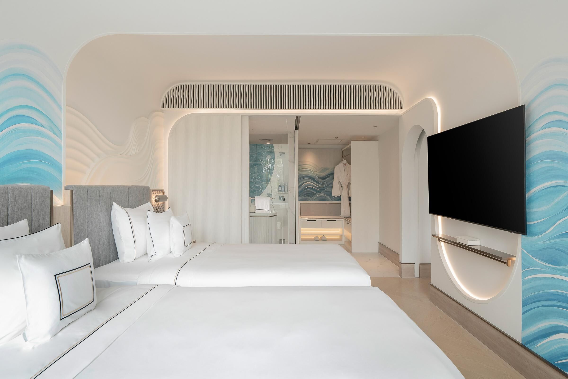 A modern hotel room with a large bed, a flat-screen TV, and a bathroom visible through an open door.