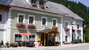A traditional building with a green facade, multiple windows, and flower boxes. - Pension am Lackenbach (Gaming)
