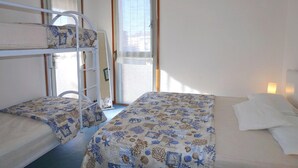 A room with bunk beds, a window with curtains, and a bedside lamp.