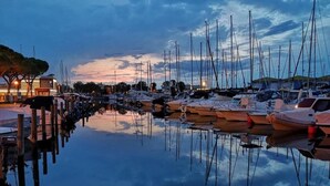 A marina with boats docked at wooden piers, surrounded by calm water reflecting the sky.