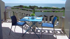 Un balcon avec une table et des chaises, donnant sur la mer.
