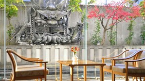 A traditional Chinese-style mural with intricate dragon designs on a wall, a wooden table with chairs, and a vase with flowers. - KKRDOGOYUDUKI (Matsuyama)