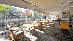 A modern indoor seating area with wooden furniture and large windows overlooking a garden. - KKRDOGOYUDUKI (Matsuyama)
