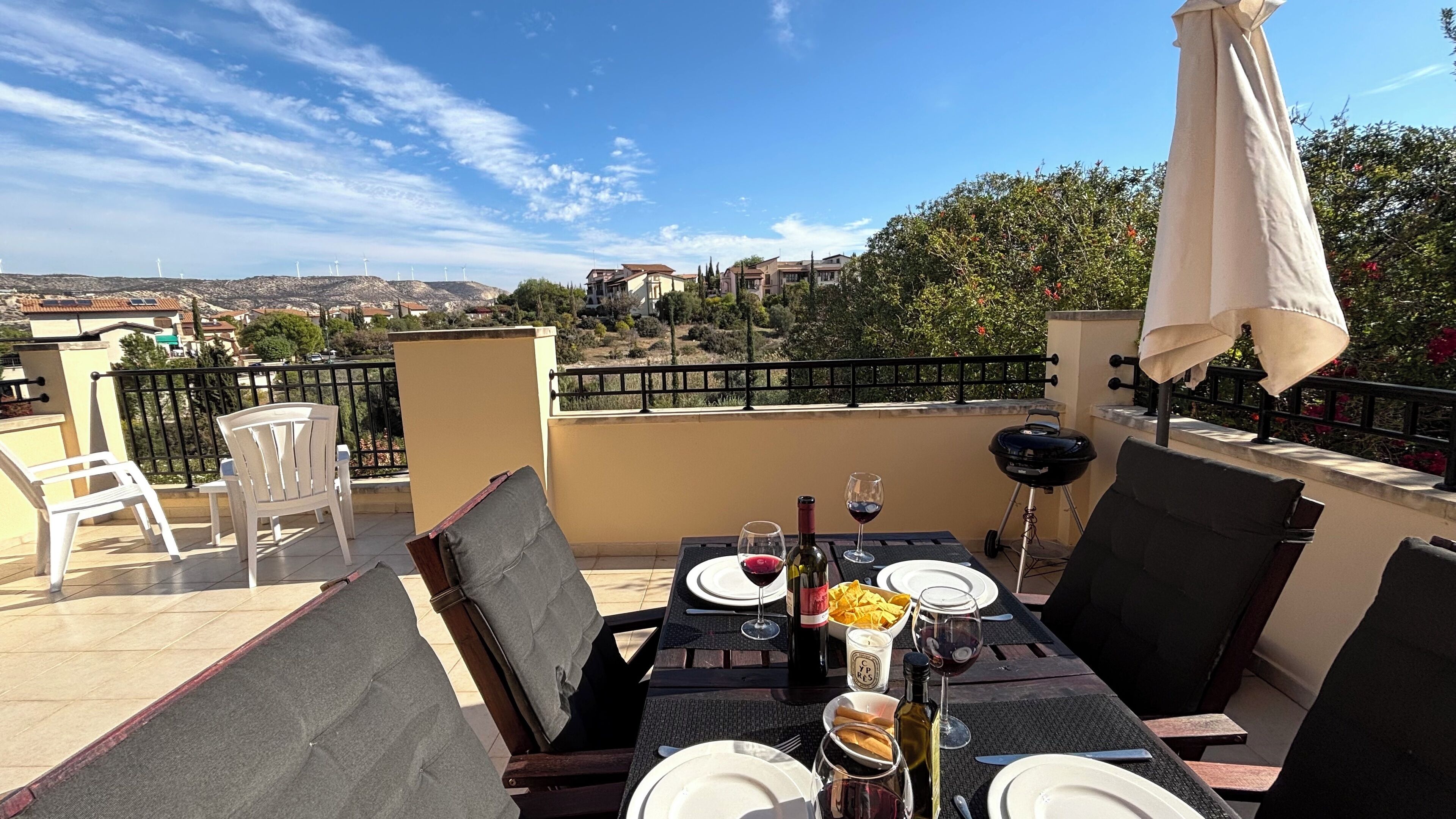 A table set for two with a view of wind turbines and houses in the background.