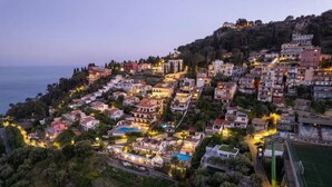 A coastal town at dusk with buildings, a swimming pool, and a tennis court.