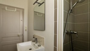 Un baño con un lavamanos blanco, un espejo y una ducha.