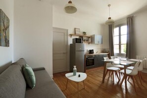 A compact living space with a kitchenette, a dining area, and a sofa. - Le Ronsardien - Quiet, comfortable apartment (Tours)