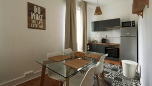 A modern kitchen with a glass dining table, white chairs, and a kitchen island.