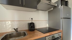 A modern kitchen with a stainless steel sink, a Bosch coffee maker, a built-in oven, and a refrigerator.