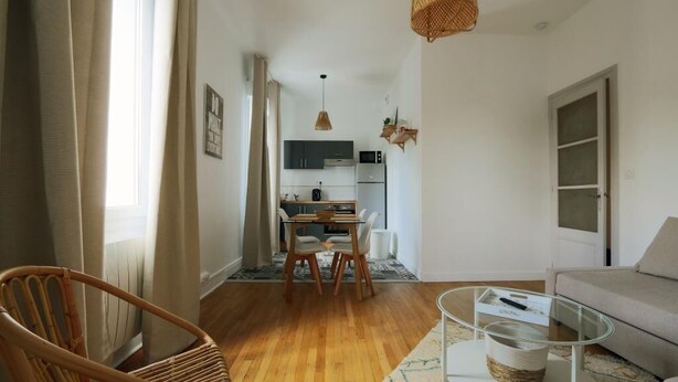 A modern living room with a sofa, a glass coffee table, and a dining area with a table and chairs.
