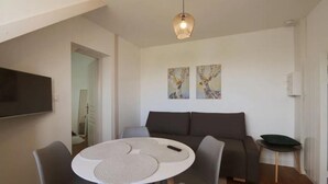 A modern living room with a round dining table, grey sofa, and artwork on the wall. - Le Rabelaisien, La Belle Tourangelle (Tours)