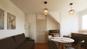 A compact living space with a sofa, dining table, chairs, and a kitchenette. - Le Rabelaisien, La Belle Tourangelle (Tours)
