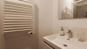 A modern bathroom with a white sink, a mirror, and a towel rack. - Le Rabelaisien, La Belle Tourangelle (Tours)