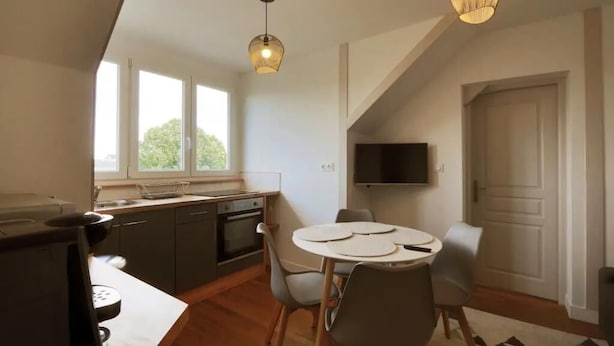 A modern kitchen with a dining area, large windows, and a TV mounted on the wall. - Le Rabelaisien, La Belle Tourangelle (Tours)