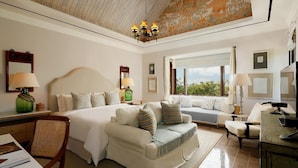 Une chambre d’hôtel avec un grand lit, un canapé, un bureau et une chaise. Il y a une fenêtre donnant sur l’extérieur.