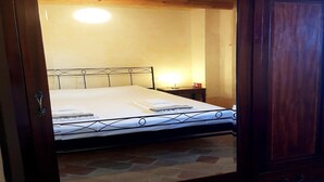 A neatly made bed with a metal headboard, a bedside table with a lamp, and a wooden ceiling. - Manor in Marche with Pool and Adriatic Views (Monsano)
