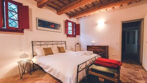 A bedroom with a bed, a nightstand, a lamp, a suitcase, and a painting on the wall. - Manor in Marche with Pool & Adriatic Views (Monsano)
