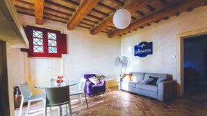 A living room with a dining area, a purple armchair, a sofa, a fan, and a sign that reads "Umbrella". - Manor in Marche with Pool & Adriatic Views (Monsano)