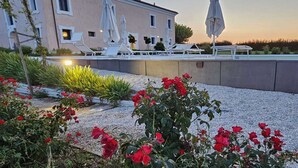 A building with a pool area, outdoor seating, and a garden with red flowers. - Manor in Marche with Pool & Adriatic Views (Monsano)