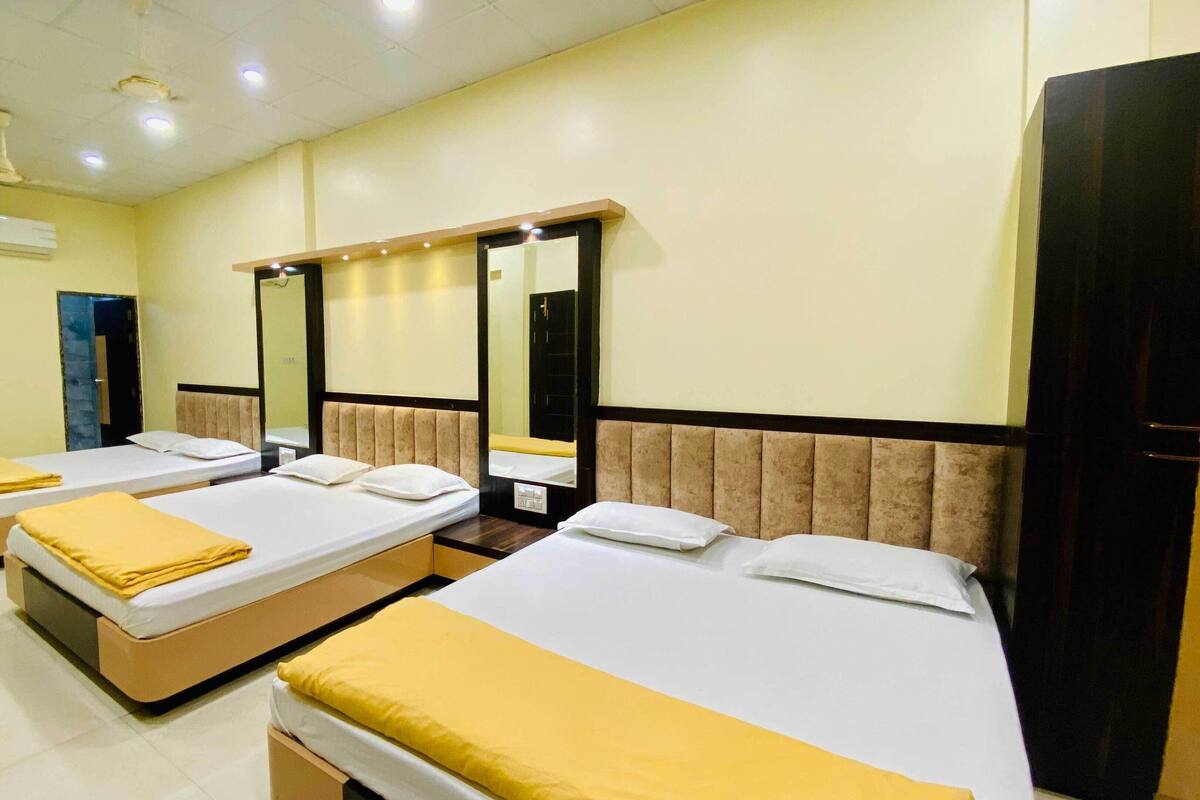 Ein Hotelzimmer mit drei Einzelbetten, jedes mit einem Kopfteil und einer gelben Decke.