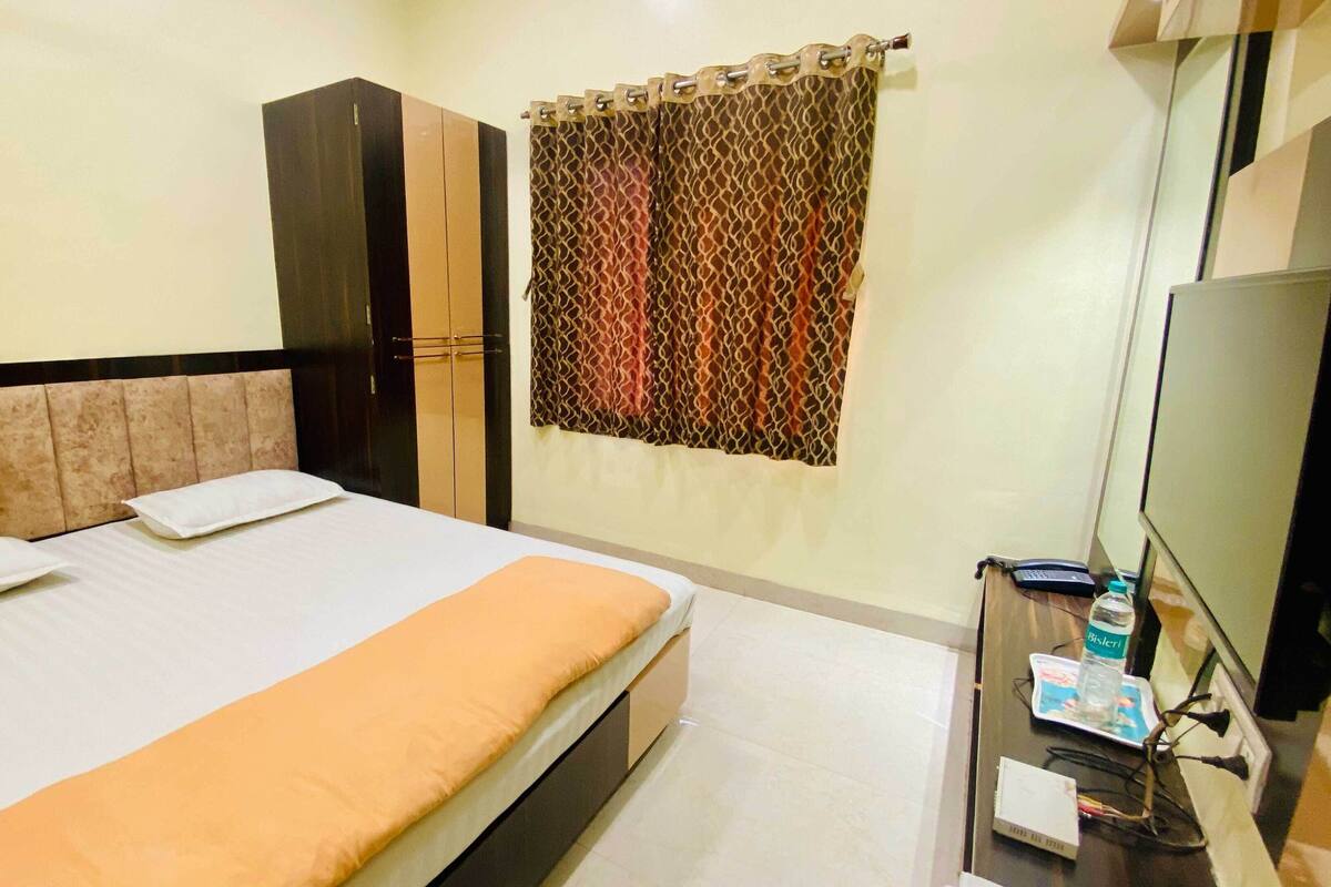 Ein Hotelzimmer mit Bett, Kleiderschrank, Fernseher und Vorhang.