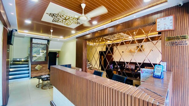A reception desk with a modern design, a clock, and a sign indicating check-in and check-out times. - Hotel Panchavati Palace (Khandwa)