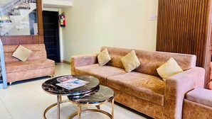 A room with a sofa, a coffee table, and a fire extinguisher on the wall. - Hotel Panchavati Palace (Khandwa)