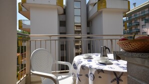 A balcony with a table set for two, a white chair, and a basket of fruit. - Renewed house in the town center (Bibione)