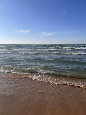 A beach with waves, clear sky, and a sandy shore. - Holland Downtown Lux Condo: City Views, King Bed (Holland)