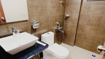 Un baño con lavamanos, inodoro y ducha blancos.