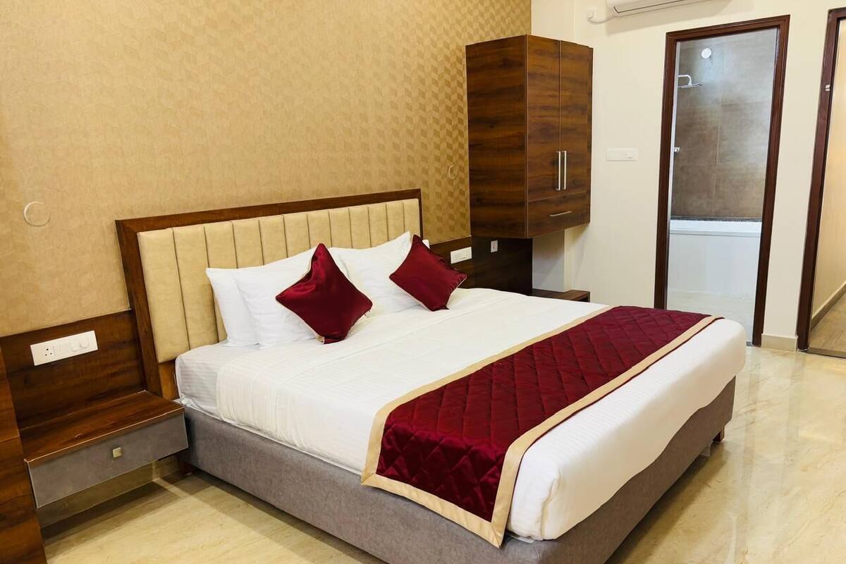 A hotel room with a bed, wooden wardrobe, and a door leading to a bathroom.