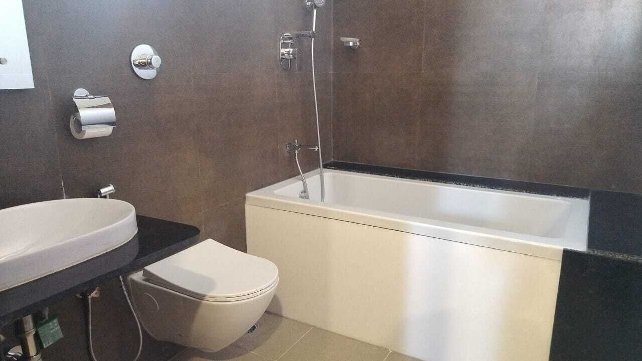 Un baño con una bañera blanca, un inodoro blanco y un lavabo sobre encimera negra.