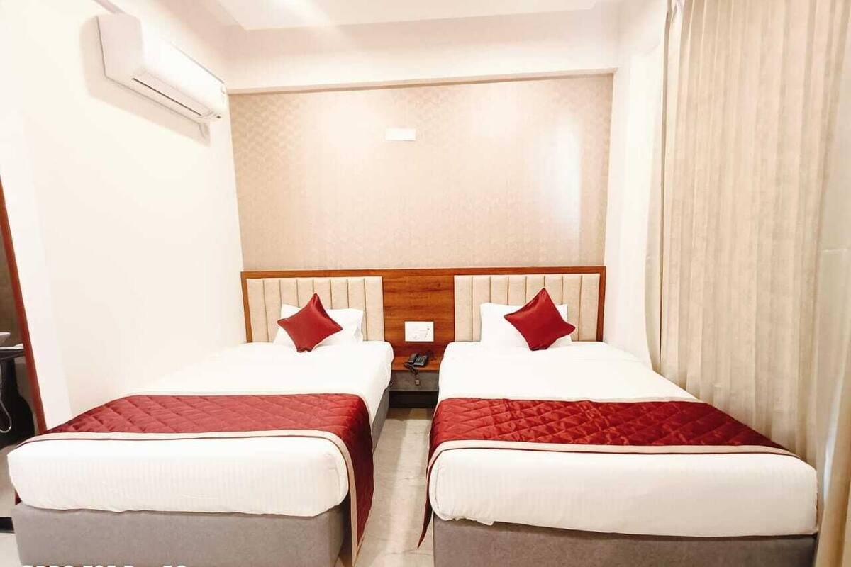 A hotel room with two beds, a wooden headboard, a nightstand, and a telephone.