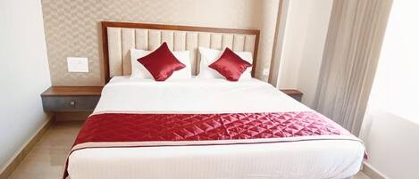 A hotel room with a large bed, a headboard, and a nightstand.