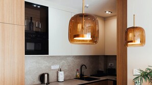 A modern kitchen with wooden cabinets, a black countertop, and two pendant lights. - Belgrade Rooftop Experience, Modern Luxury & Views (Beograd)