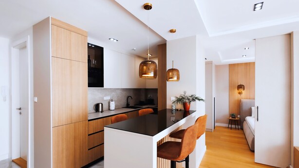 A modern kitchen with a central island, wooden cabinets, pendant lighting, and a small dining area with bar stools. - Belgrade Rooftop Experience, Modern Luxury & Views (Beograd)