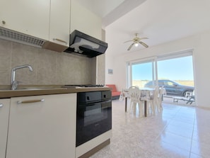 A modern kitchen with a built-in oven, a sink, and a ceiling fan.