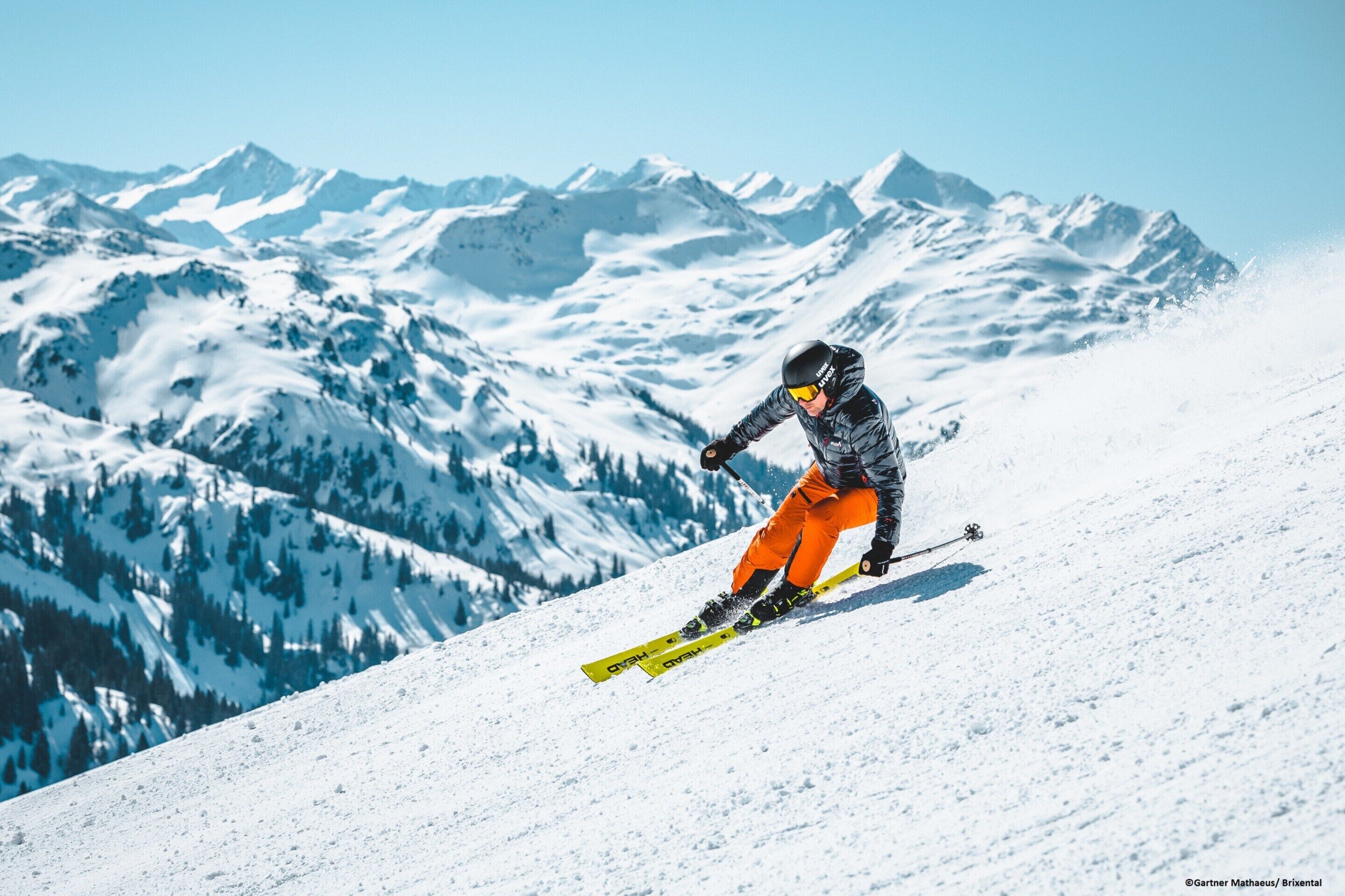 A skier on a snowy slope with mountains in the background.