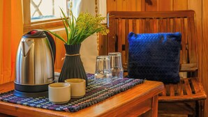 Ein Holztisch mit Wasserkocher, Tassen und einer Blumenvase.