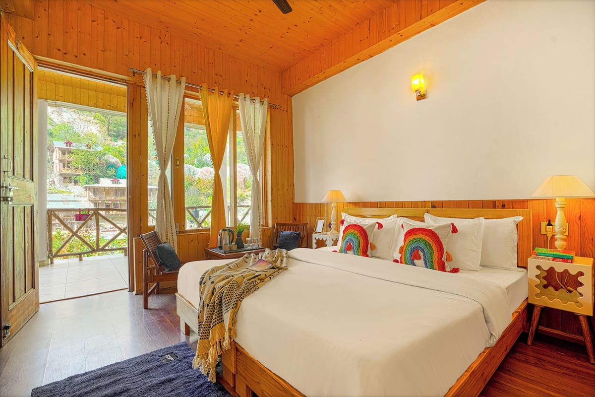 A wooden cabin bedroom with a large bed, a nightstand, a chair, and a view of the outside.