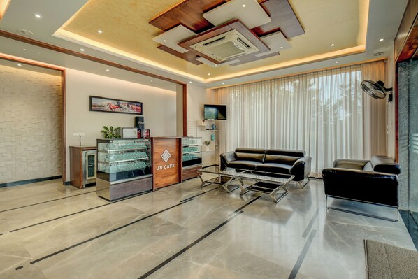 A modern living room with a sofa, a coffee table, and a JN Cafe counter. - Hotel J N stay (Mysore)