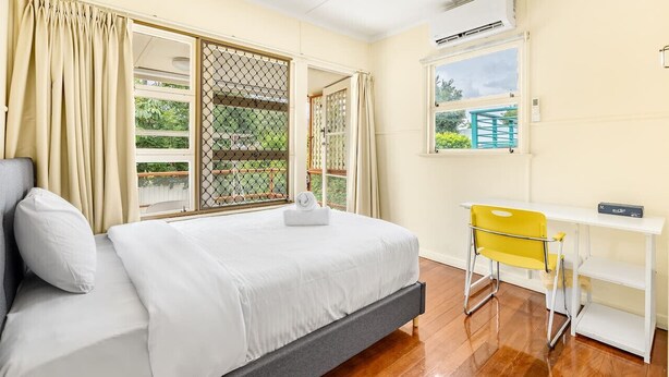 Un dormitorio con cama, escritorio y ventana.