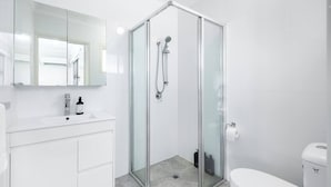 A modern bathroom with a glass-enclosed shower, a white sink, and a toilet. - Affordable Studio – Steps from UQ/ Shops/ Transit (Saint Lucia)