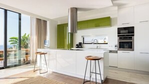 Uma cozinha moderna com uma ilha grande, armários brancos e detalhes verdes.