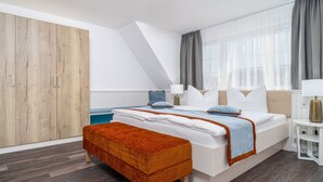A modern bedroom with a large bed, a wooden wardrobe, and a window with curtains. - Dascha vacation apartment in the Baltic seaside resort of Dierhagen (Dierhagen)