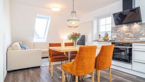 A modern kitchen with a dining area, featuring a wooden table, orange chairs, and a chandelier. - Dascha vacation apartment in the Baltic seaside resort of Dierhagen (Dierhagen)