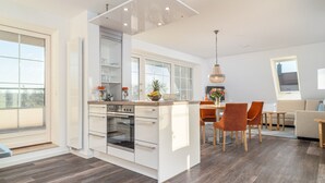 A modern kitchen with a central island, built-in appliances, and a dining area with a table and chairs. - Vacation apartment Inga in the Ostseebad Dierhagen (Dierhagen)