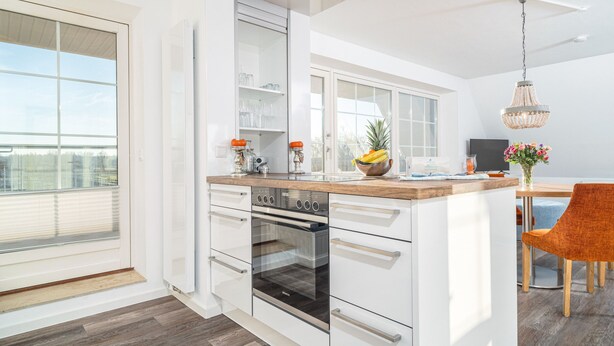 A modern kitchen with white cabinetry, a wooden countertop, and a built-in oven. - Vacation apartment Inga in the Ostseebad Dierhagen (Dierhagen)