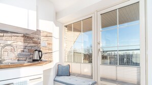 A modern kitchen with a stone backsplash, a built-in bench with a cushion, and a large sliding glass door leading to a balcony. - Vacation apartment Inga in the Ostseebad Dierhagen (Dierhagen)